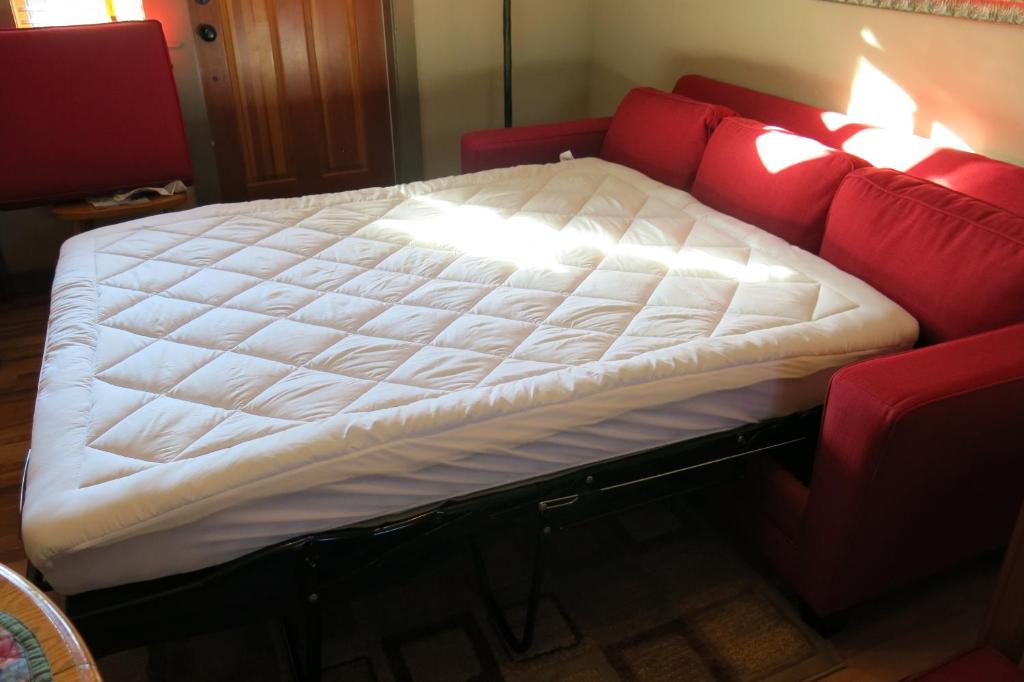 a bed on top of a red couch at A Shack In The Woods in Port Renfrew