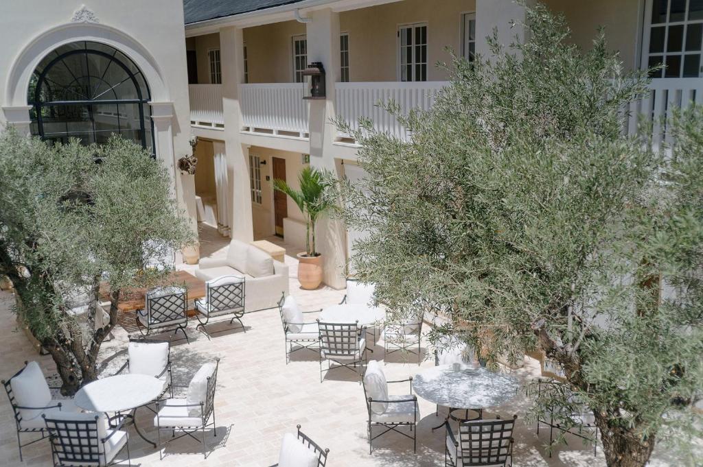 an outdoor patio with chairs and tables and trees at Cara Hotel in Los Angeles
