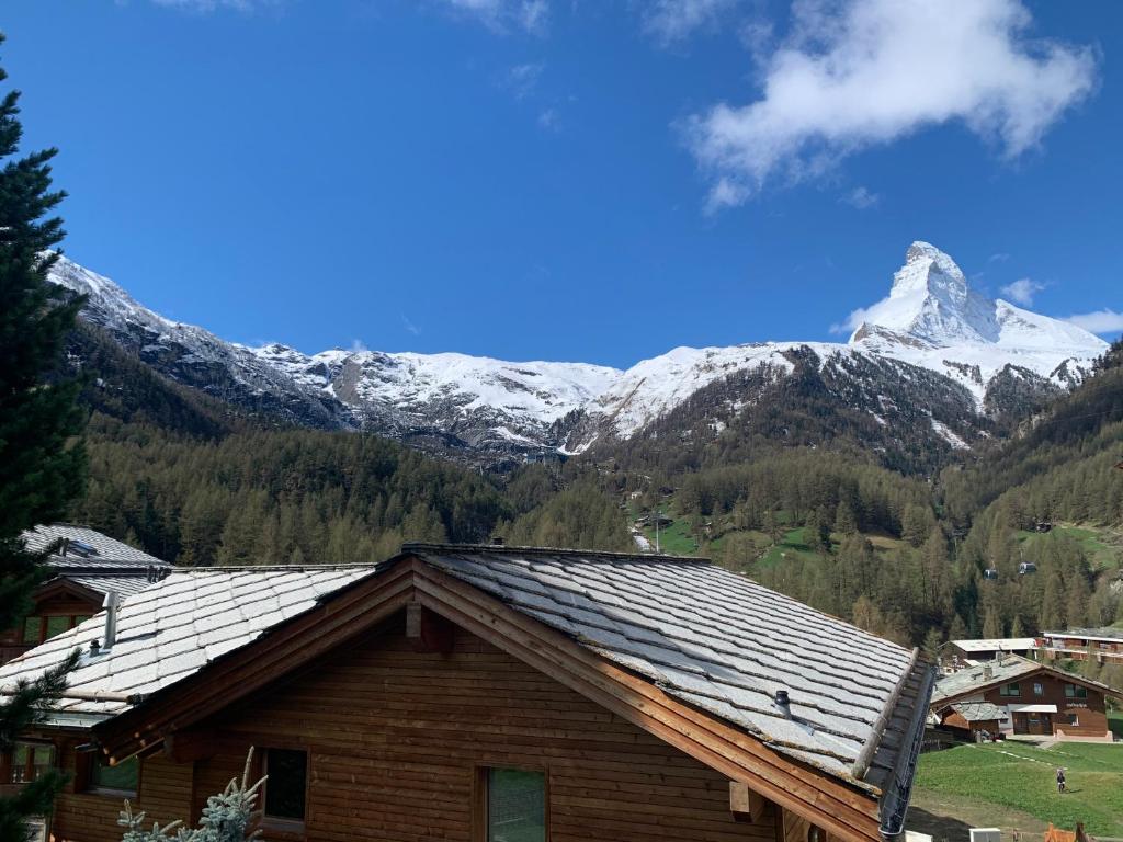 a house with a snow covered mountain in the background at Matterhorn Panorama Apartment in Zermatt