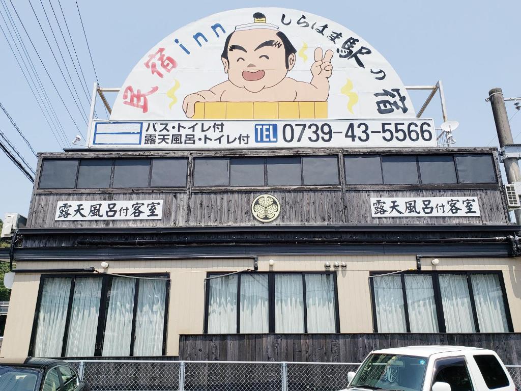 um edifício com uma grande placa em cima em Minshuku Inn Shirahama Ekinoyado em Shirahama