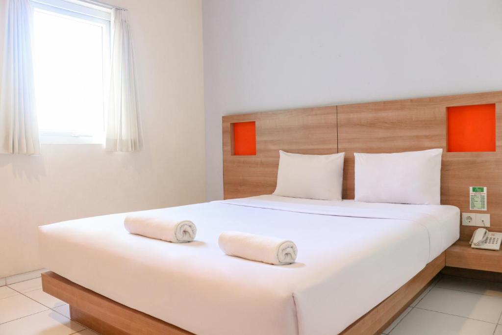 a bedroom with a large white bed with two towels on it at LeGreen Suite Waihaong in Ambon