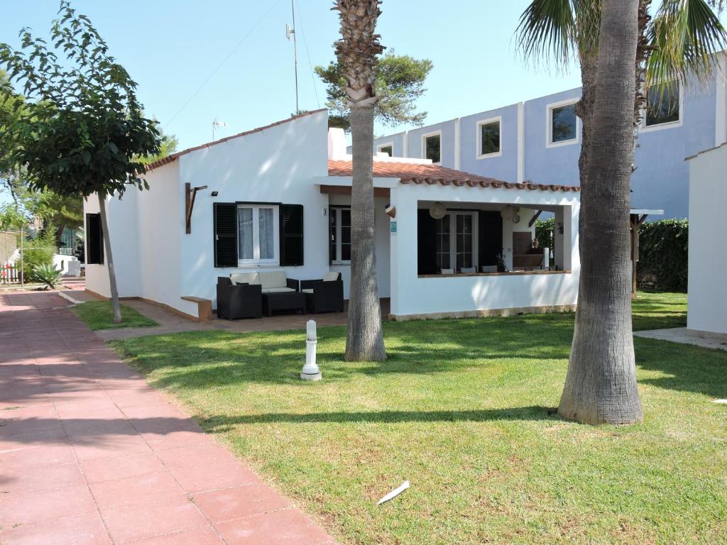 a white house with two palm trees in the yard at Chalet Cerca de la Playa in Cala'n Bosch