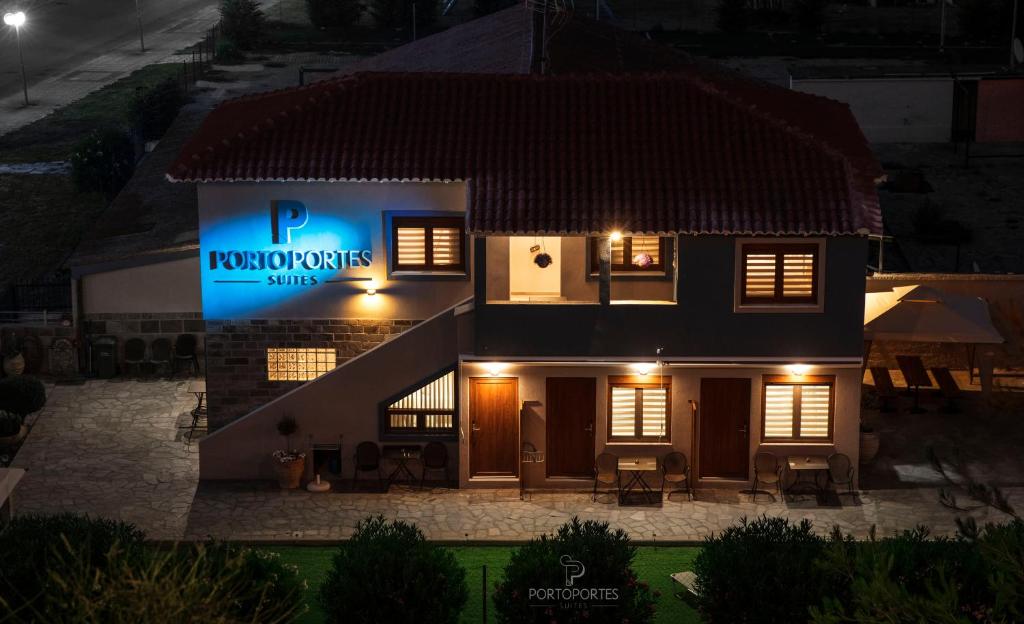 a house with a sign on the side of it at night at PORTO PORTES suites in Nea Potidaea