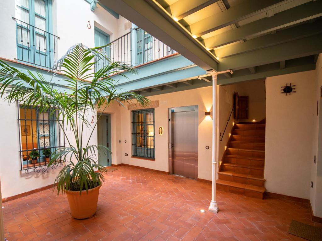 um corredor de um edifício com uma escada e uma planta em Casas de Sevilla - Apartamentos Vidrio 7 em Sevilha