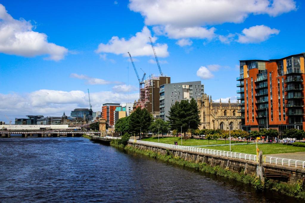 a river in a city with buildings and a bridge at Riverview Apartments in Glasgow