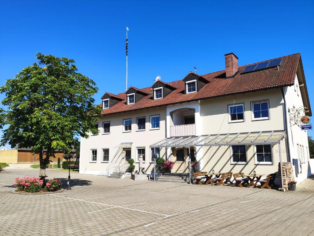 um grande edifício branco com uma árvore em frente em Landgasthof Braun em Mindelstetten