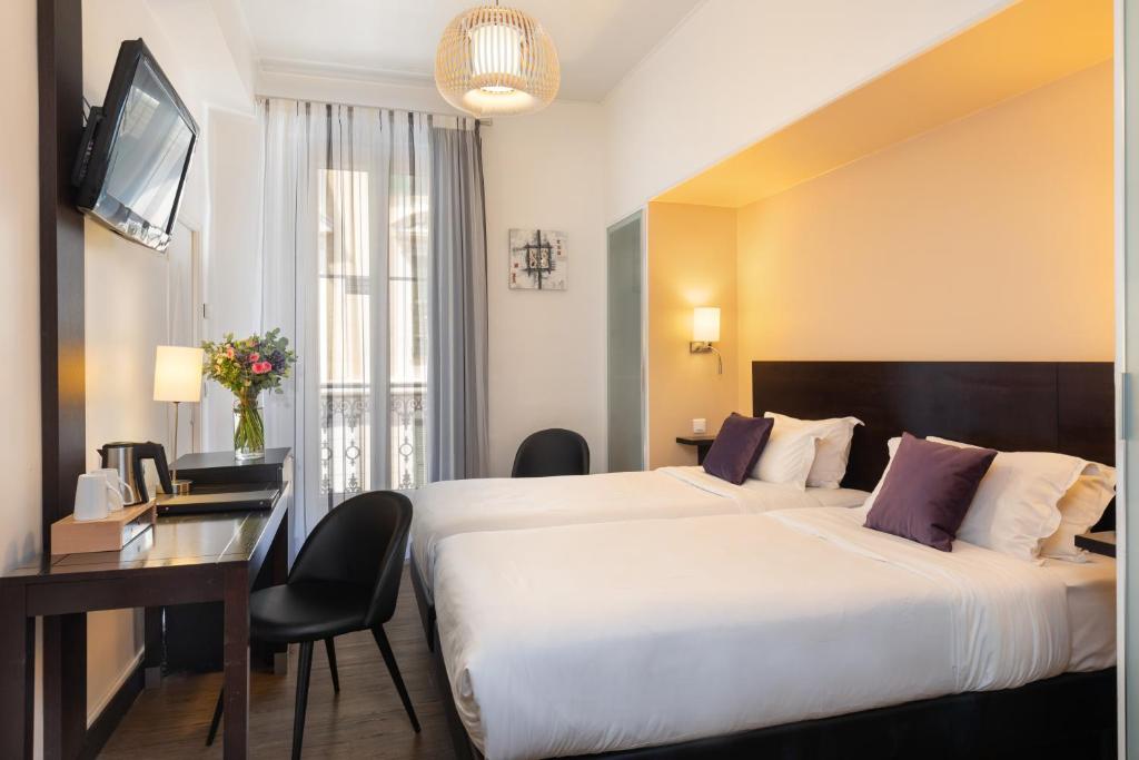 a hotel room with a large bed and a desk at Hotel Florence Nice in Nice