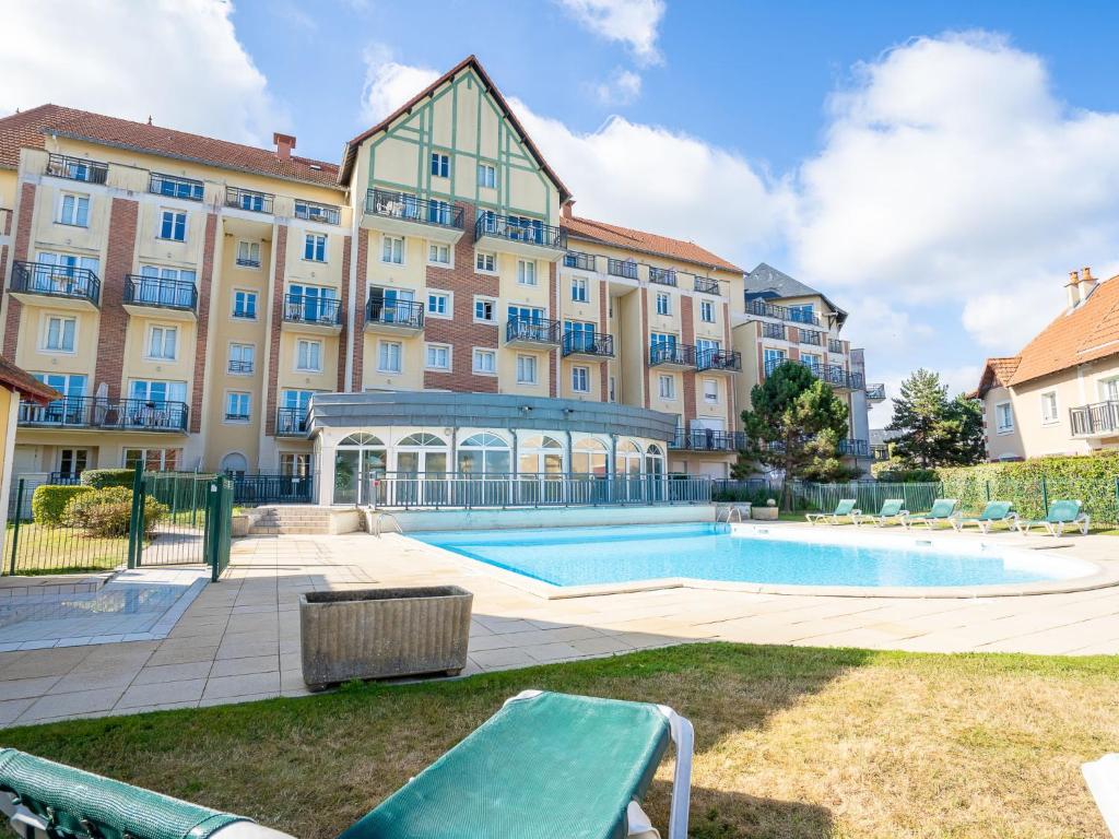 a large building with a swimming pool in front of it at Apartment Port Guillaume-6 by Interhome in Cabourg