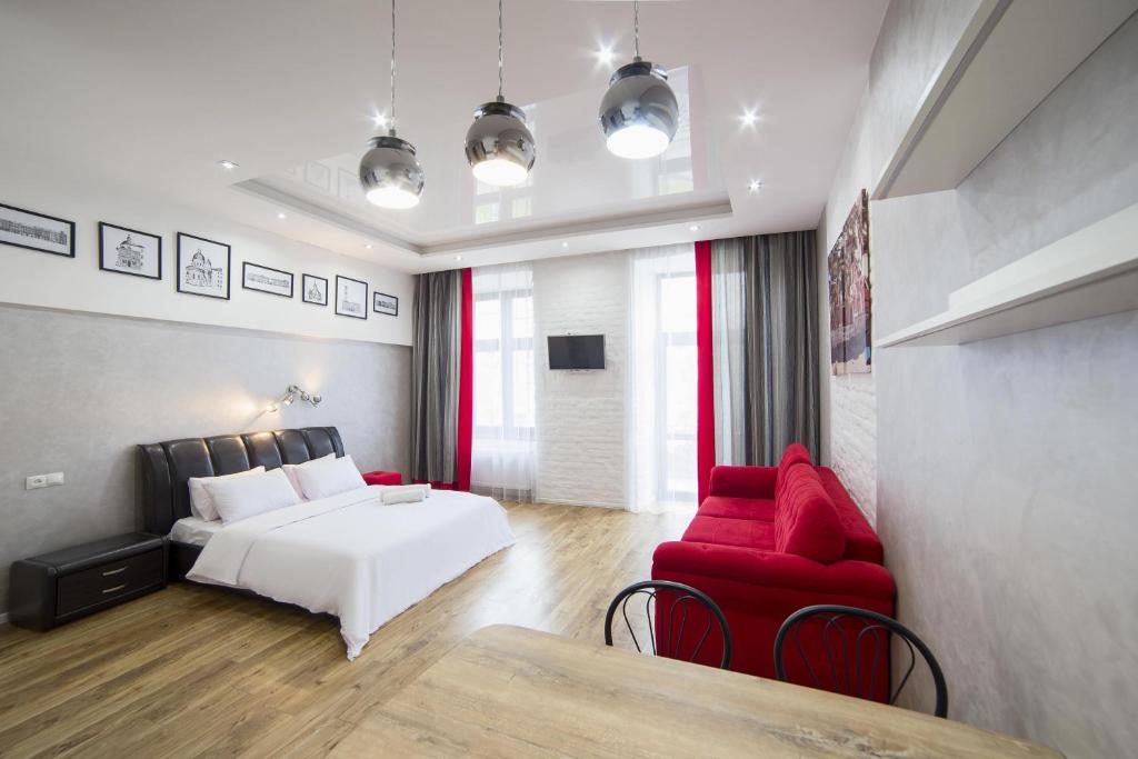 a bedroom with a white bed and a red couch at Lviv4U in Lviv