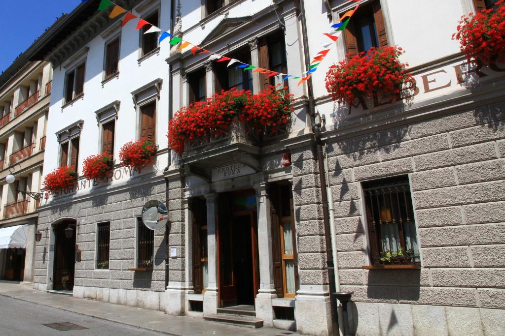 a building with flower boxes and flags on a street at Albergo Roma in Tolmezzo