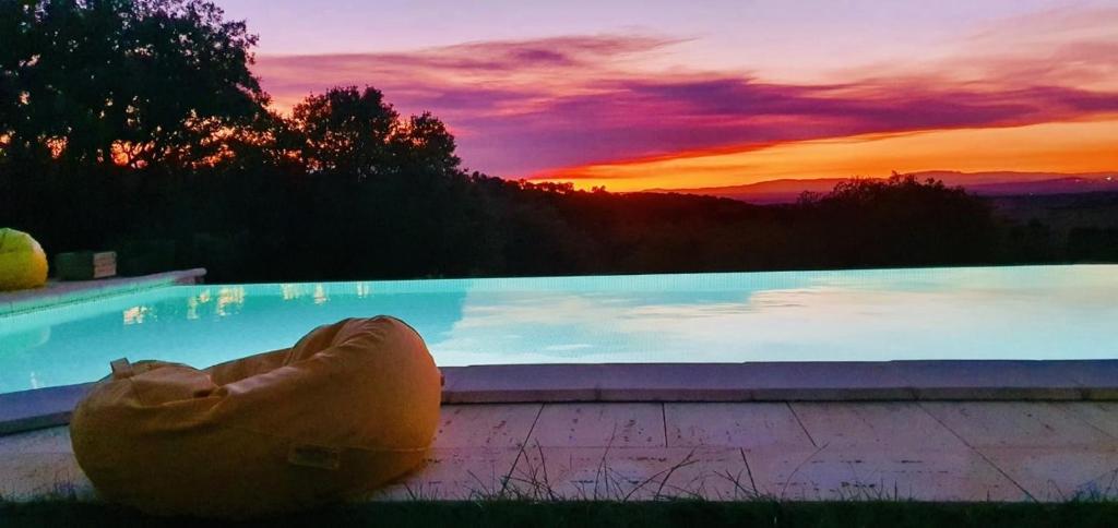 a large swimming pool with a pillow in front of a sunset at Monte Vale Mosteiro in Rosmaninhal