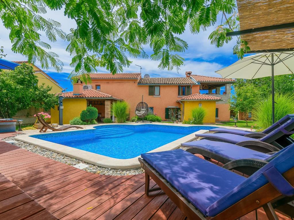 a pool with chairs and an umbrella in a yard at Holiday Home Loreta by Interhome in Čabrunići