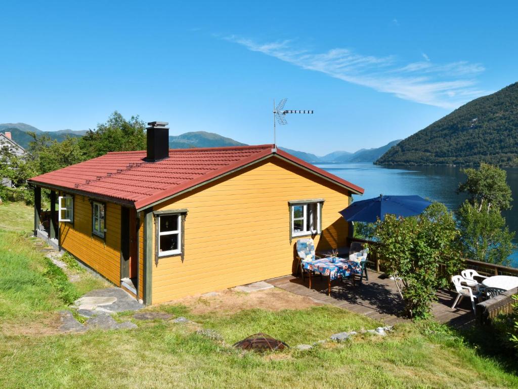 a yellow cottage with a view of a lake at Holiday Home Nausthammar - FJS706 by Interhome in Davik
