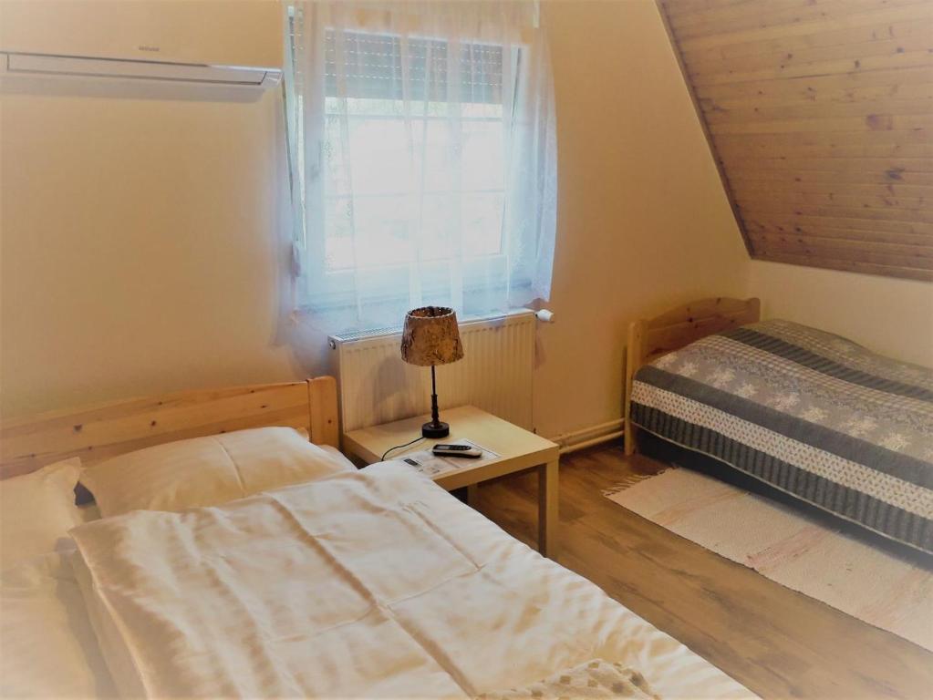 a bedroom with two beds and a lamp on a table at Napocska Vendégház Harkány in Harkány
