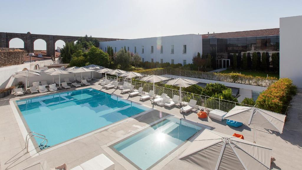 - une vue sur la piscine bordée de chaises et de parasols dans l'établissement M'AR De AR Aqueduto, à Évora