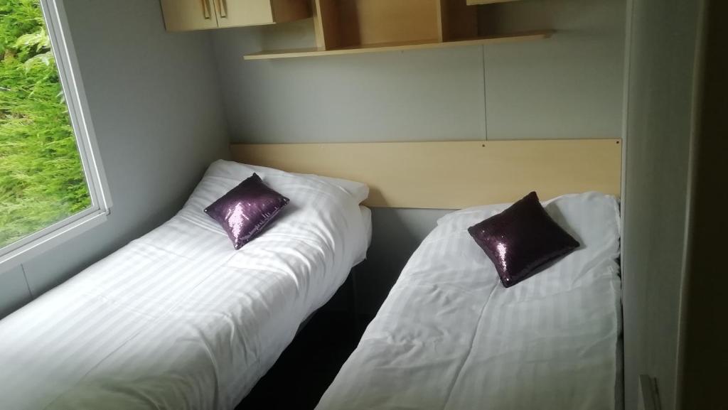 2 camas en una habitación con almohadas moradas en Static Caravan for hire, budget friendly, en Edimburgo