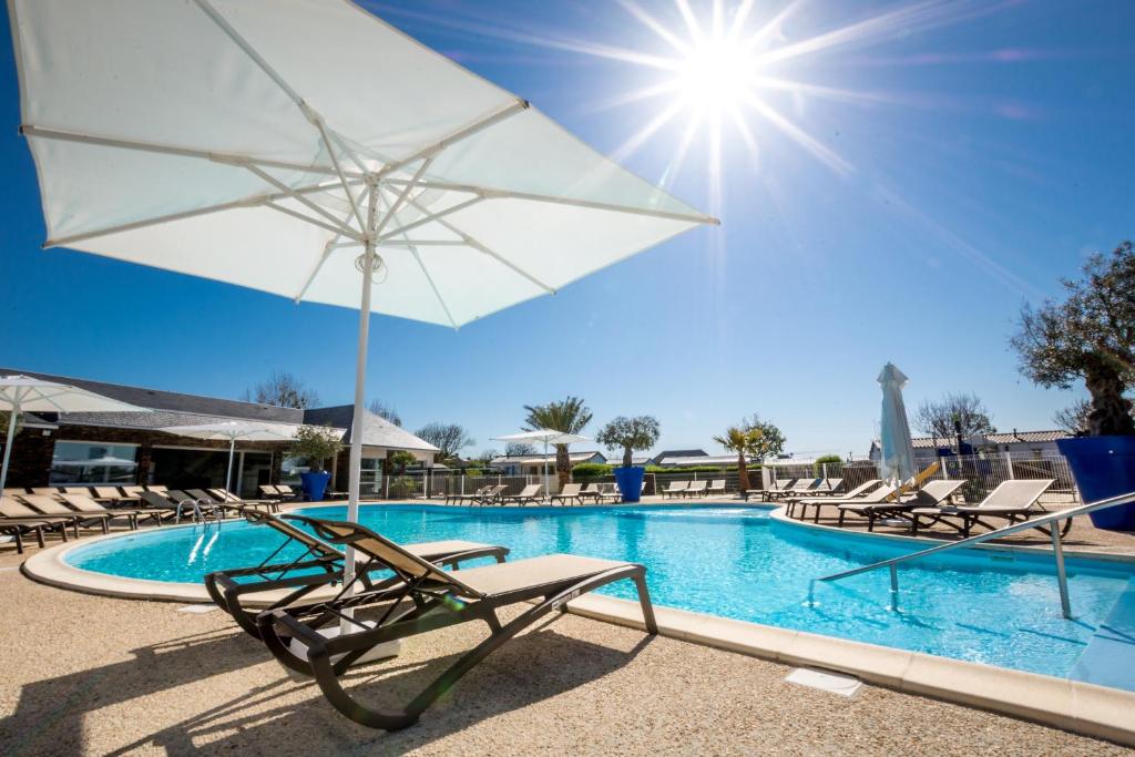 een zwembad met stoelen en een witte parasol bij M&V Resort Camping in Langrune-sur-Mer