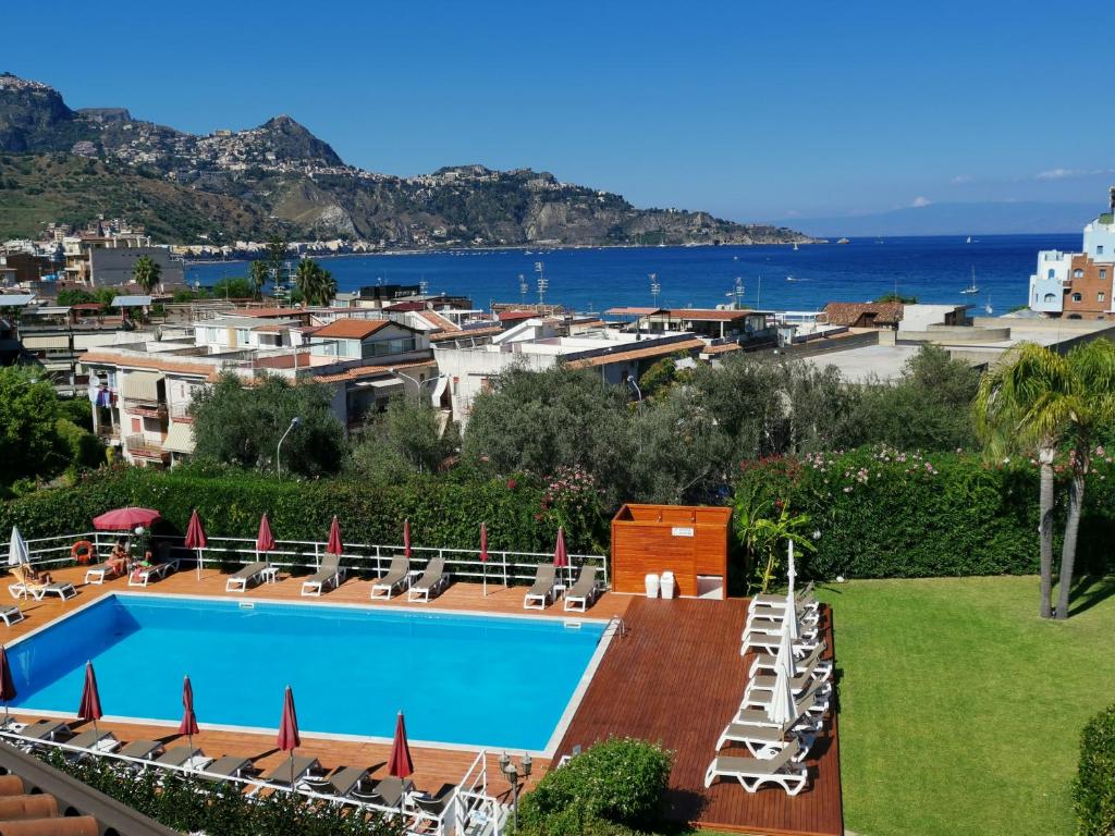 a swimming pool with chairs and the ocean in the background at Residence Villa Giardini in Giardini Naxos