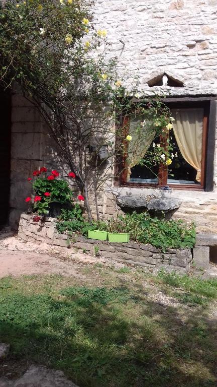 petite maison au paradis في La Neuvelle-lès-Scey: نافذة من مبنى حجري مع ورود في ساحة