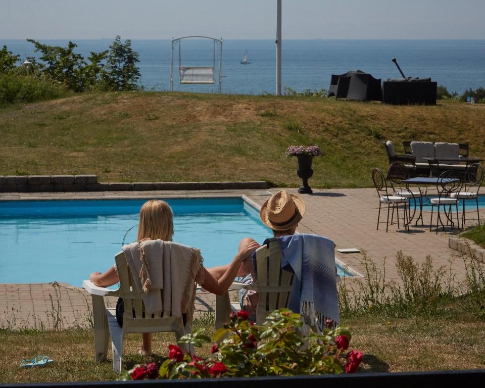 a man and woman sitting in chairs near a swimming pool at Löderup Strandbad Hotell och Restaurang in Löderup