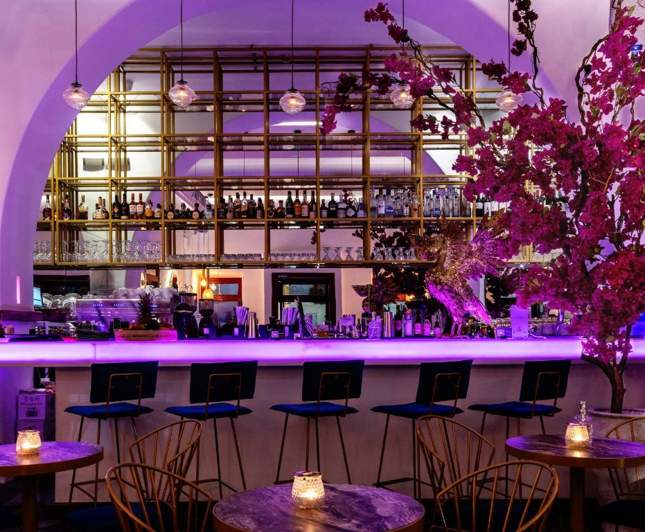 a bar with tables and chairs in a room with purple lighting at The TownHouse Mykonos in Mýkonos City