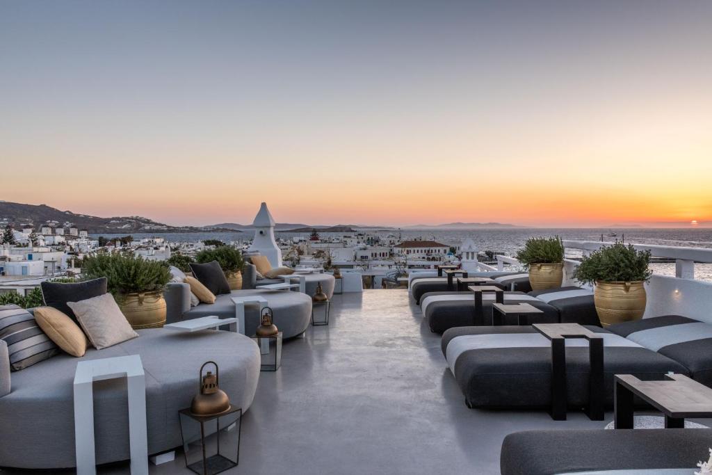 a hotel rooftop with couches and tables and a sunset at The TownHouse Mykonos in Mýkonos City