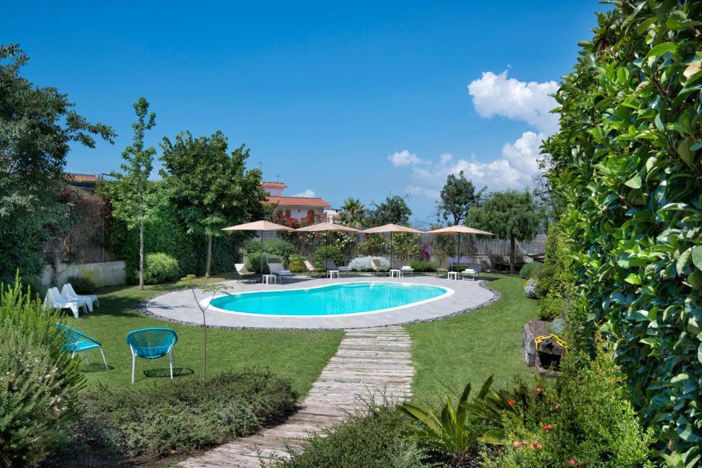 una piscina en un patio con sillas y sombrillas en Maison Di Fiore B&B en Ercolano