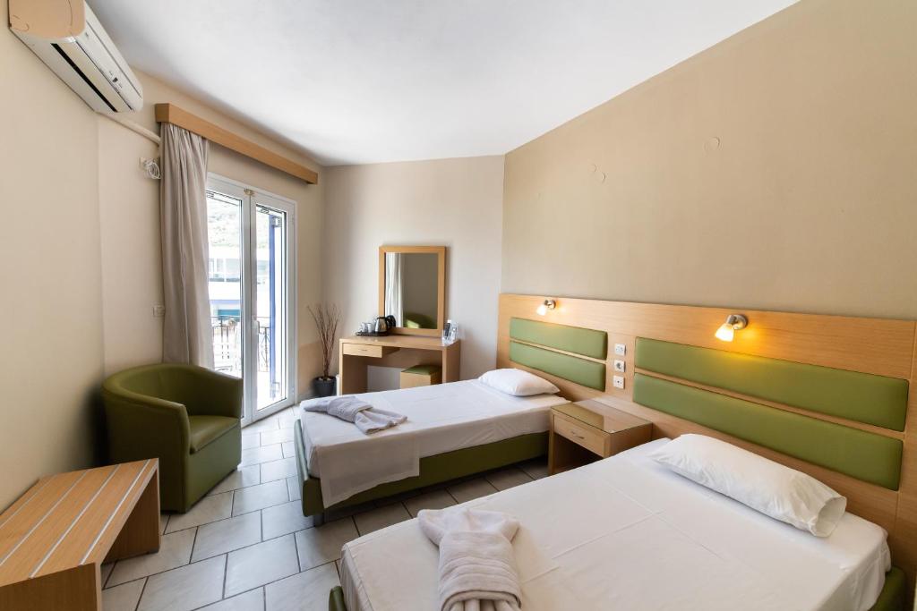 a hotel room with two beds and a chair at Surf Hotel in Vasiliki