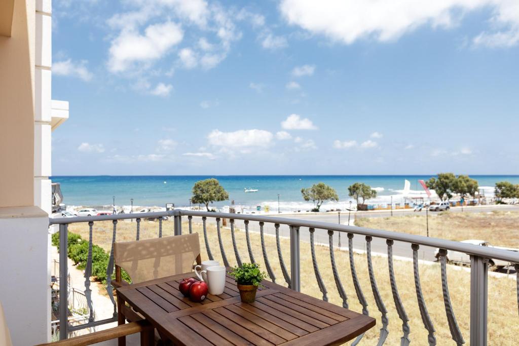 Una mesa en un balcón con vista a la playa. en Kahlua Bay Apartments, en Hersonissos