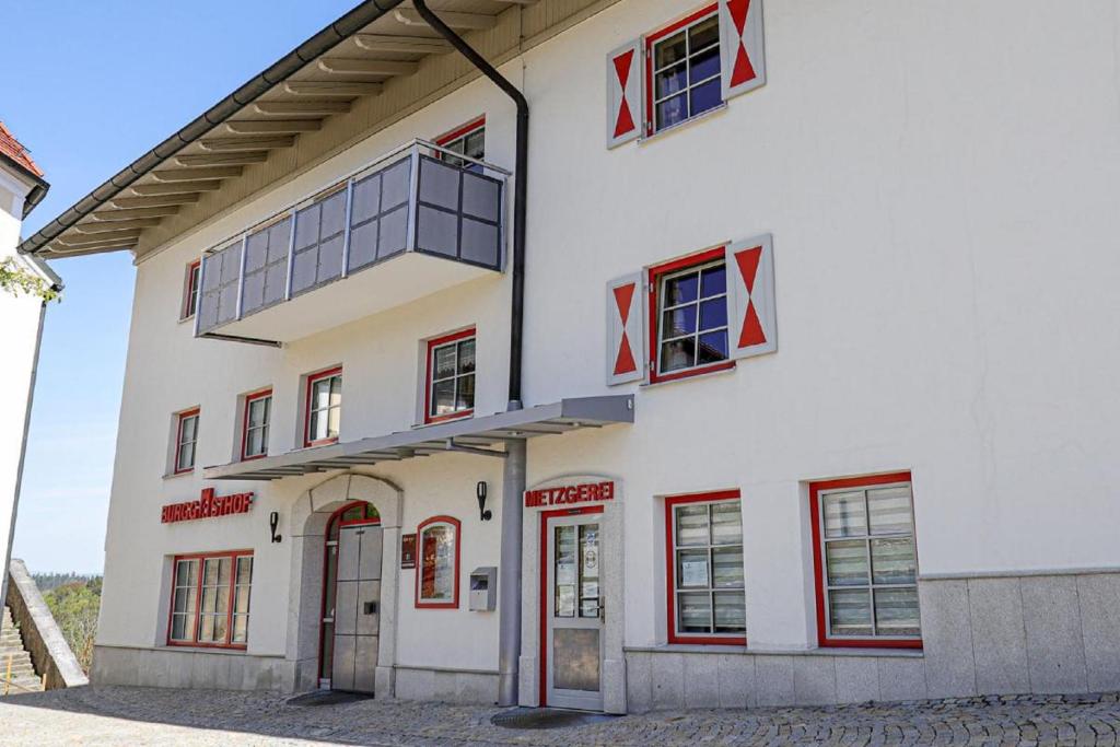 un edificio blanco con ventanas rojas. en Burggasthof Hauptmann, en Kollnburg