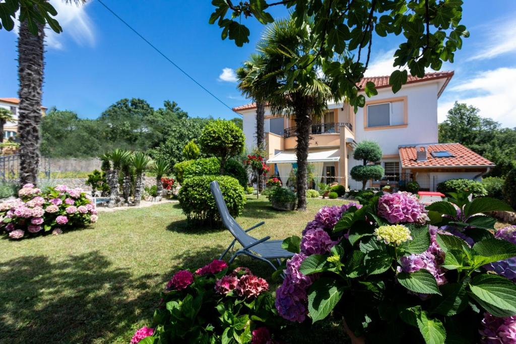 krzesło w ogrodzie domu z kwiatami w obiekcie Apartment Marangunija w mieście Malinska
