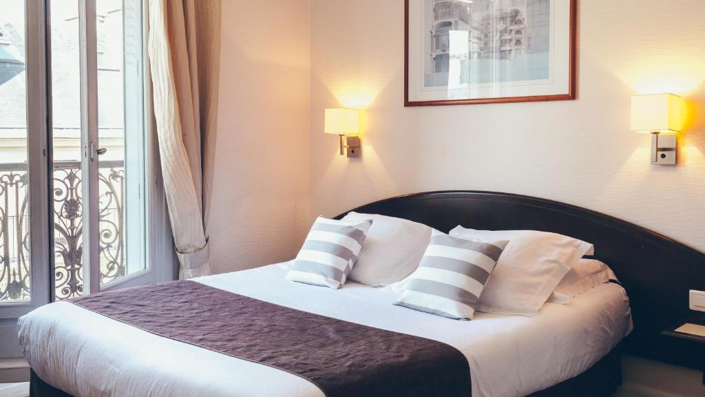 a bedroom with a bed with pillows and a balcony at Excelsior Opera in Paris