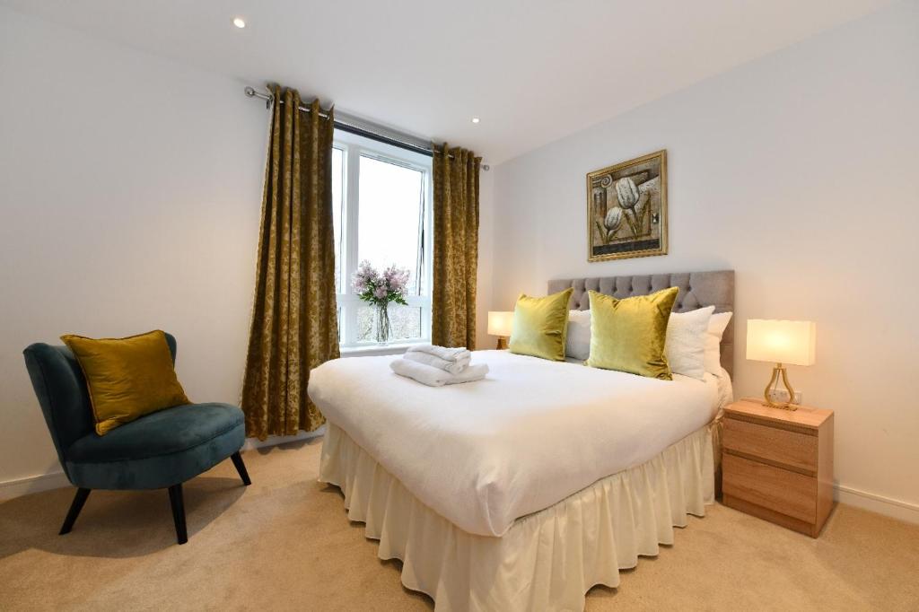 a bedroom with a bed and a chair and a window at Kew Bridge Apartments in London