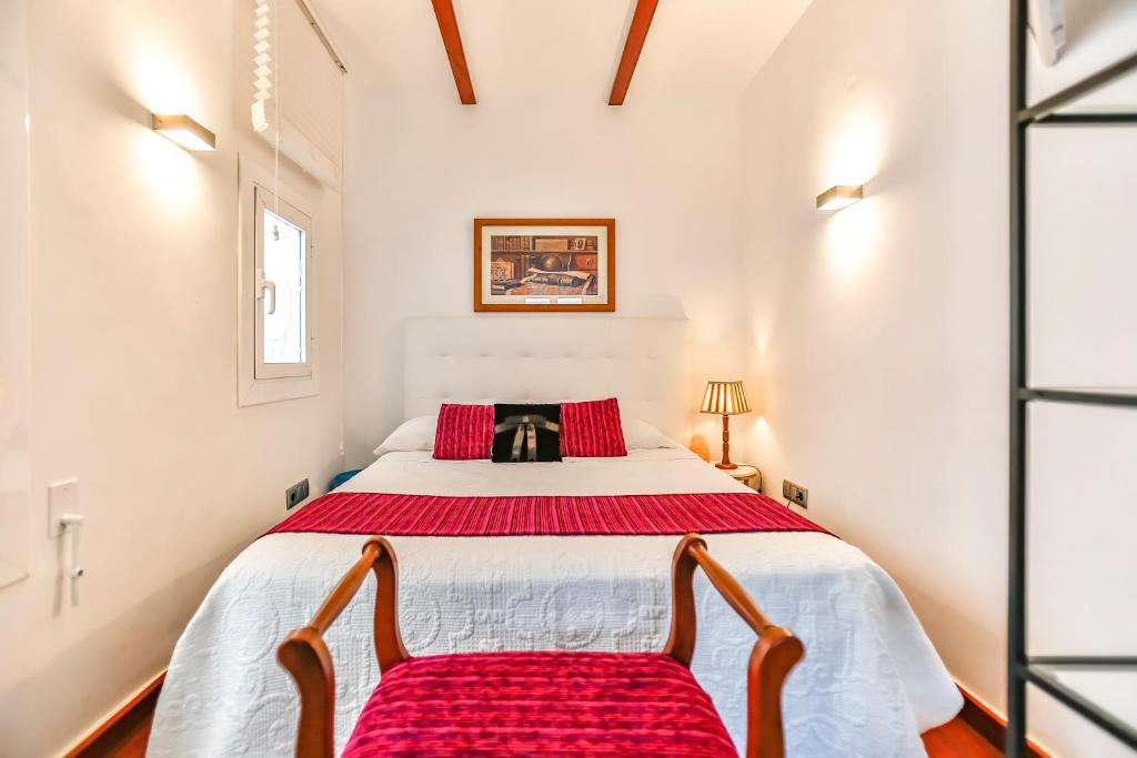 a bedroom with a large white bed with two chairs at Ghat Apartments Montroig in Sitges