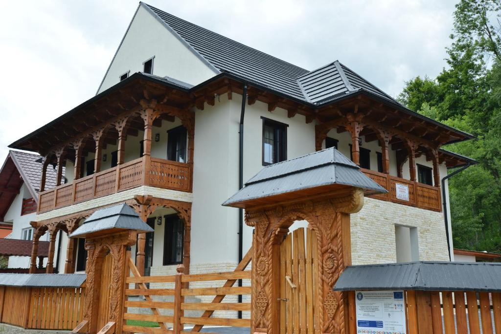 een groot wit huis met een houten hek bij Pensiunea ARMONIA in Văleni