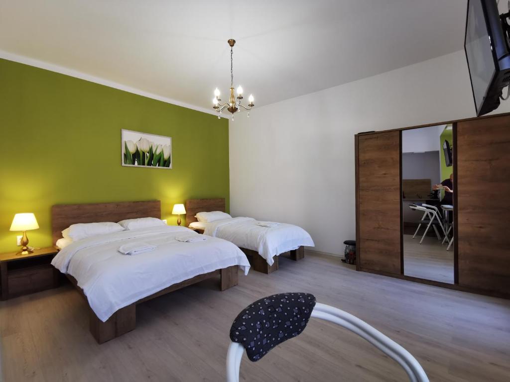 a bedroom with two beds and a mirror at Ambient Deluxe Apartman in Gyula
