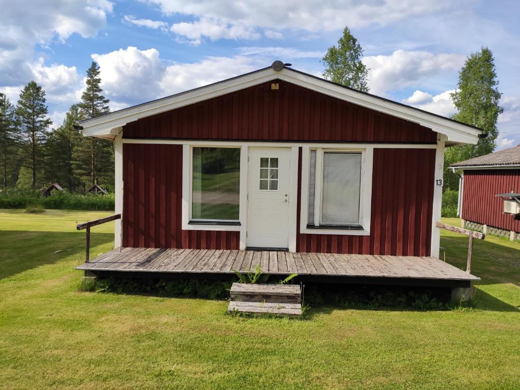 Stuga Ekesberget Stugby في Ekshärad: منزل أحمر صغير مع شرفة خشبية
