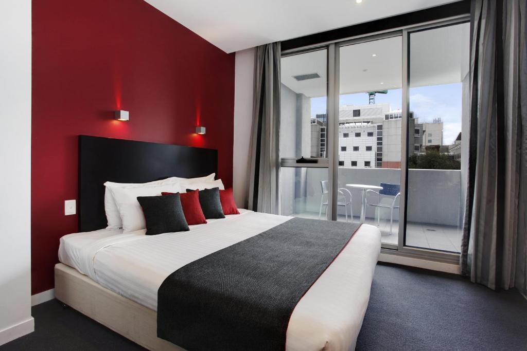 a bedroom with a large bed with a red wall at Adara Hotel Richmond in Melbourne