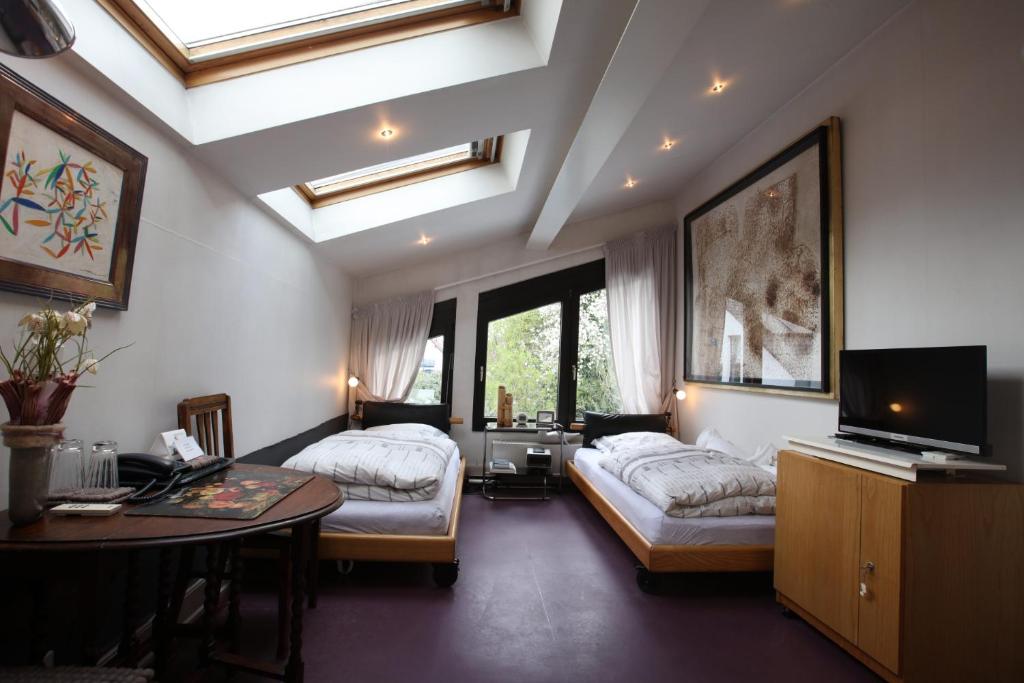 a bedroom with two beds and a table and a tv at Air Boardinghouse Tulip Stockum, zu Fuß - 3 Minuten zur Messe in Düsseldorf