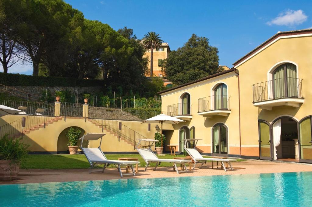 a pool with chairs and umbrellas next to a building at Villa Agnese in Sestri Levante
