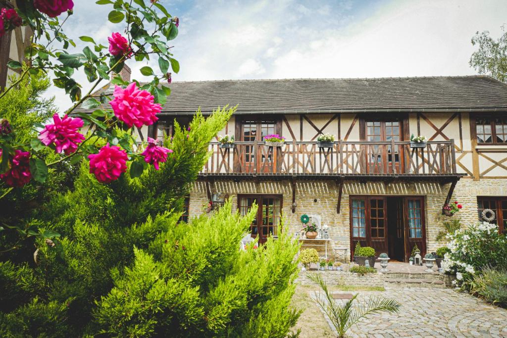 a house with a balcony and pink roses at Au fil de l'eau in Fourges