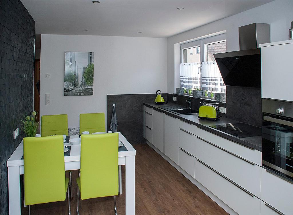 uma cozinha com uma mesa e cadeiras amarelas em Hochwertige und moderne Ferienwohnung Huber em Neuweiler