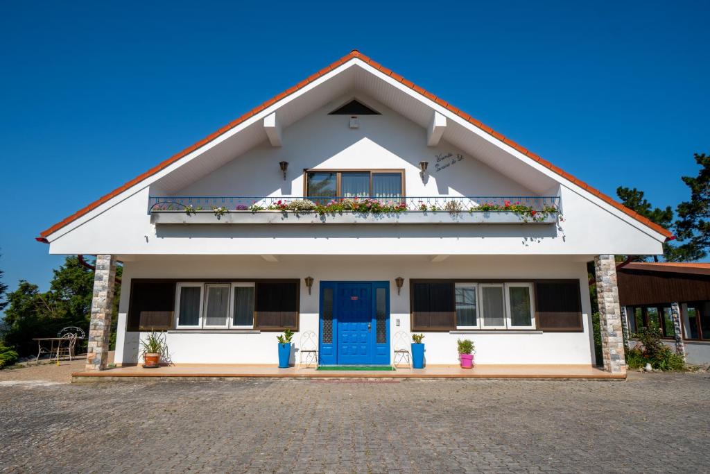 a white house with a blue door and a balcony at Refúgio Rural - Eco Villa in Caldas da Rainha