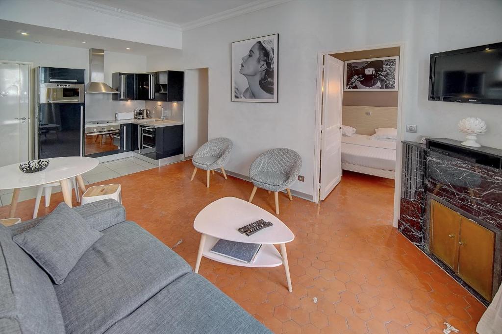 カンヌにあるAppartement Cannes Centreのリビングルーム(グレーのソファ付)、キッチンが備わります。