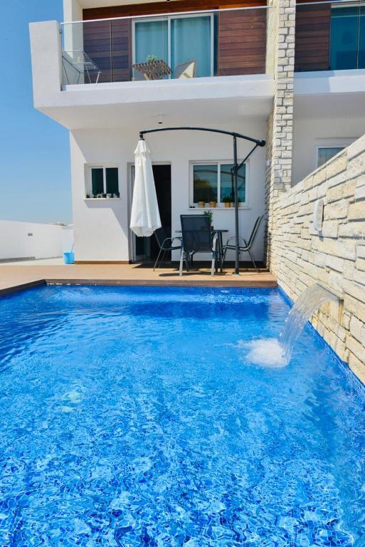 a large blue swimming pool in front of a house at Melanos Residence 2 bdrm townhouse with private pool in Khlorakas