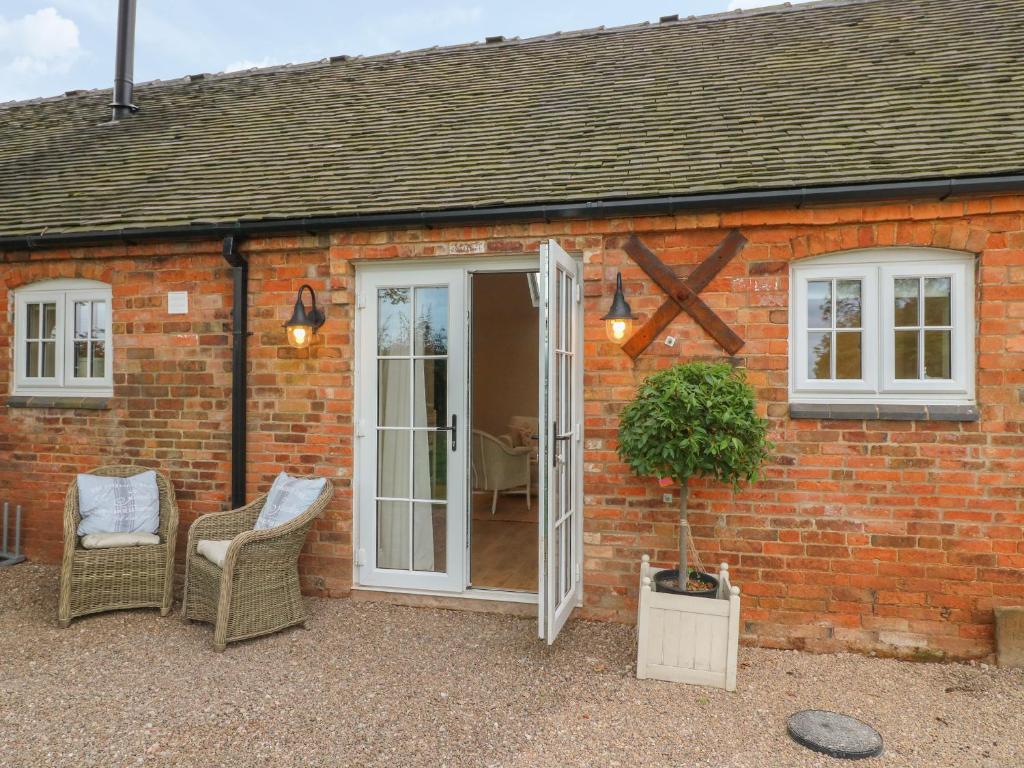 a red brick house with a white door and chairs at March Hare in Ashbourne