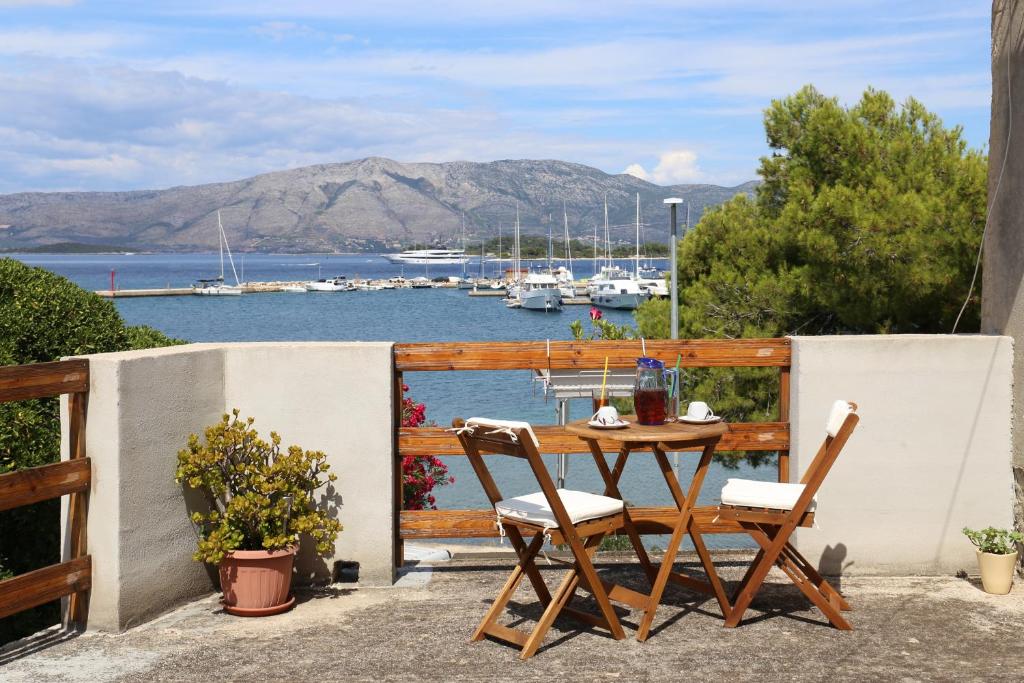 einen Tisch und Stühle auf einem Balkon mit Hafenblick in der Unterkunft Coosy rooms KATARINA in Lumbarda