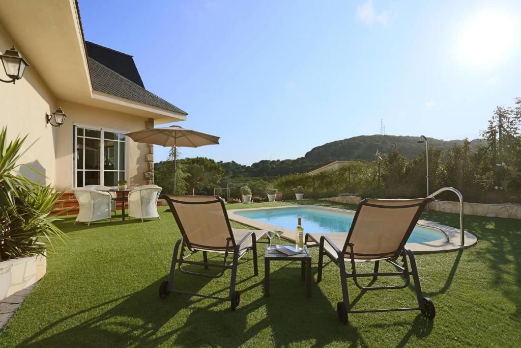 2 Stühle und ein Tisch neben einem Pool in der Unterkunft Homestay Villa Estrella - Costa Brava in Calella