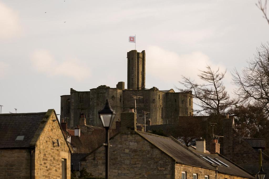 an old castle sitting on top of a city at Warkworth House Hotel in Warkworth
