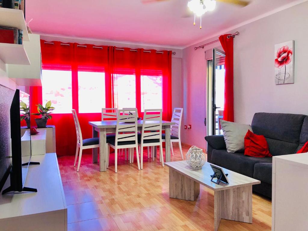 ein Wohnzimmer mit einem Tisch und roten Vorhängen in der Unterkunft CENTRICO LABRADORES 15 in Peñíscola